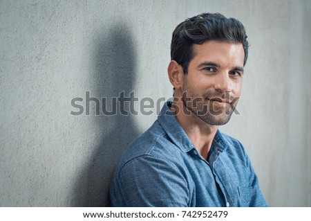 Handsome young man posing on grey background. Portrait of satisfied businessman against grey wall. Close up face of fashionable latin man on grey background.