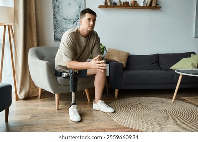 Handsome young man with a prosthetic leg sits thoughtfully in a modern living room. - Powered by Shutterstock