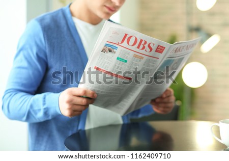 Handsome young man reading newspaper in cafe