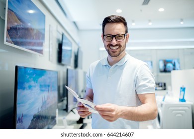 Handsome Young Man Reading The Use Instructions. Buying New Tv Set At The Tech Store.