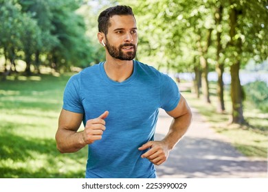 Handsome young man running in park during spring summer
