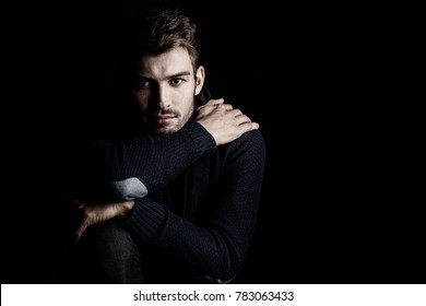 Handsome young man in scarf and sweater. Studio portrait. Autumn and winter clothing. Male fashion.