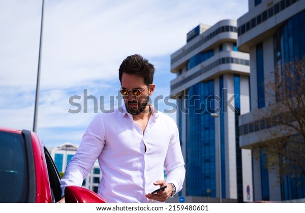 Handsome young man, sculpted body next to his red\
sports car. The man is wealthy and dressed in modern clothes.\
Sports car