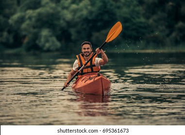 Handsome young man in sea vest is smiling while sailing a kayak - Powered by Shutterstock