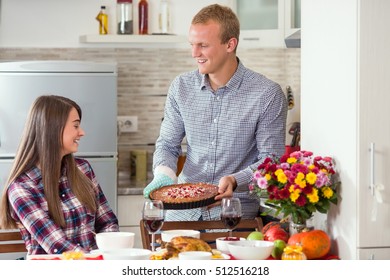 Handsome Young Man Is Serving Freshly Baked Homemade Pumpkin Pie For Thanksgiving Dinner To His Beautiful Young Wife.