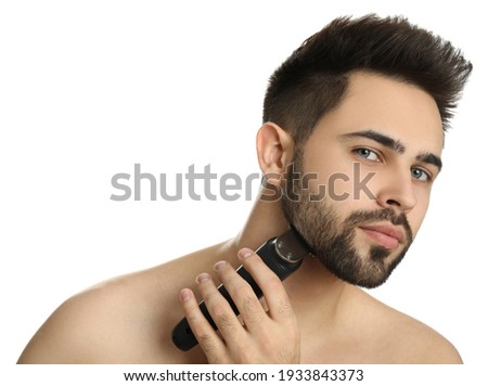 Handsome young man shaving with electric trimmer on white background