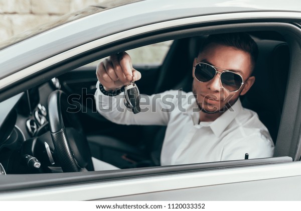 Handsome Young Man Showing Car Keys in His\
Newly Bought Auto Sitting in the Luxury\
Vehicle