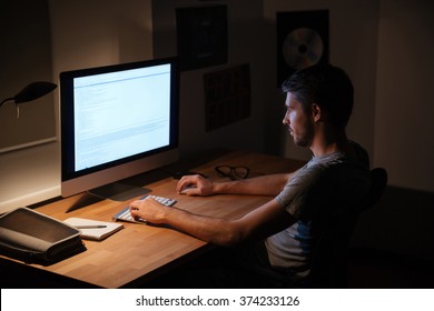暗い部屋に座ってパソコンを使うハンサムな若者写真素材 Shutterstock