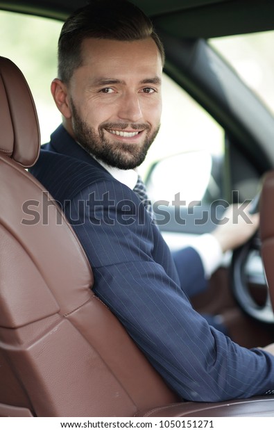 Handsome young man sitting in the front seat of a\
car looking at the\
camera