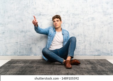 Handsome young man sitting on the floor touching on transparent screen