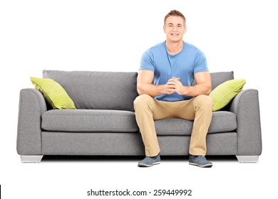 Handsome Young Man Sitting On A Modern Sofa Isolated On White Background