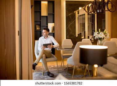 Handsome Young Man Sitting And Using Digital Tablet At Luxury Apartment