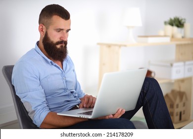 Handsome young man sitting and working on laptop computer. - Shutterstock ID 214178209