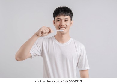 Handsome young man smiles happily and holding toothbrush.