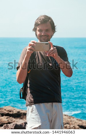 Man recording a video at seaside using modern gadgets