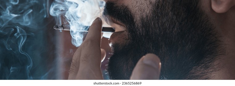 Handsome young man smoking cigarette - Shutterstock ID 2365256869