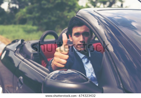 Handsome young man\
in sports car wearing\
suit.