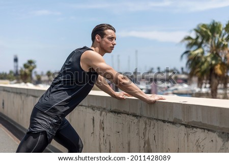 Strong Man Stretching Calf and Leaning on Wall