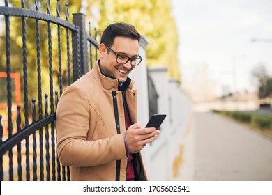Handsome young man standing on the street and hold his phone. - Shutterstock ID 1705602541