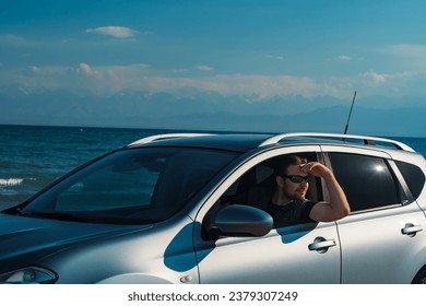 Handsome young man in sunglasses driving car on seashore at summer day - Powered by Shutterstock