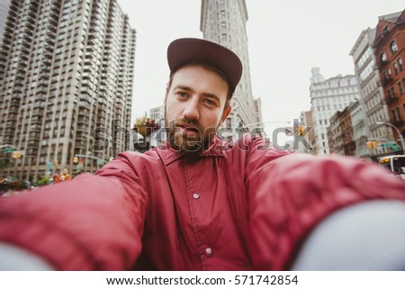Handsome young man takes selfie photo near Flat Iron building in Manhattan, New York. Cute guy in his 20s takes picture for her blog while travel.