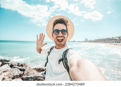 Handsome young man taking selfie at beach summer vacation - Smiling guy having fun walking outside - Summertime holidays and technology concept - Powered by Shutterstock