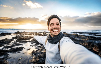 Handsome young man taking selfie pic with smart mobile phone outdoors - Traveler guy smiling at camera with sunset on background - Traveling life style and technology concept  - Powered by Shutterstock