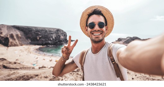 Handsome young man taking selfie with smart mobile phone at the beach - Smiling guy looking at camera outside - Summer vacation and technology concept - Powered by Shutterstock