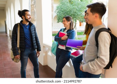 Handsome young man talking with his happy college friends while laughing together on the hallway