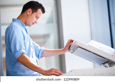 Handsome  young man using a copy machine (shallow DOF; color toned image) - Powered by Shutterstock