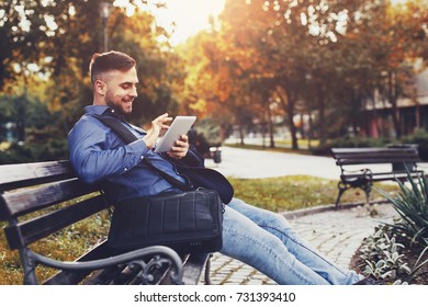 Handsome young man using digital tablet on the bench