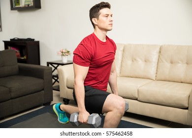 Handsome Young Man Using Dumbbells To Do Kneeling Lunges At Home