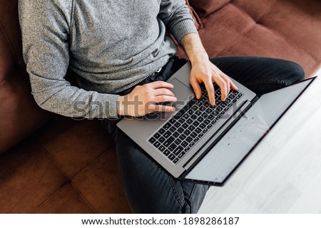 Handsome young man using laptop computer at home. Student man is reading the book. Online shopping, home work, freelance, online learning, studying concept. Distance education Stock photo © 