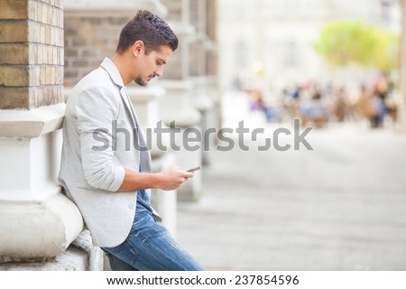 Handsome young man using mobile phone on the street
