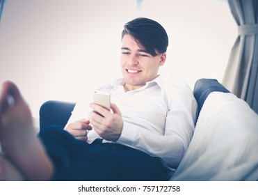 Handsome young man using smartphone at home