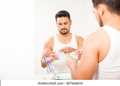 Handsome Young Man Using Some Styling Gel To Get His Hair Done In Front Of A Mirror In The Bathroom