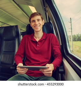 handsome young man using tablet computer on the train. traveler on the road