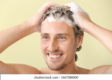 Handsome Young Man Washing Hair Against Color Background