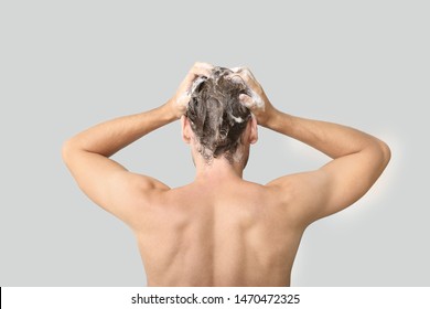 Handsome Young Man Washing Hair Against Grey Background, Back View