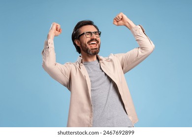 Handsome young man wearing glasses over isolated blue background very happy and excited, doing winner gesture with arms raised. Celebration concept - Powered by Shutterstock