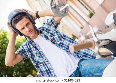 Handsome young man is wearing helmet while sitting on scooter. - Powered by Shutterstock