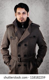 Handsome Young Man Wearing Overcoat And Standing Against Grey Wall