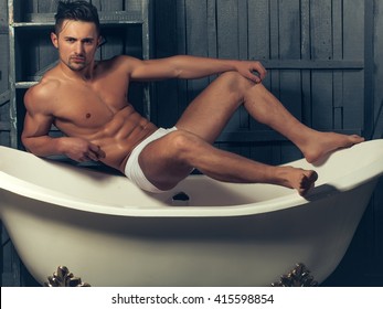 Handsome Young Man In White Panties With Sexy Bare Muscular Torso Sitting On Bathtub