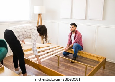 Handsome Young Man And Woman Building A Bed Frame To Assemble New Furniture Together In The Bedroom