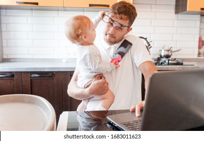 Handsome young man working at home with a laptop with a baby on his hands. Stay home concept. Home office with kids. 