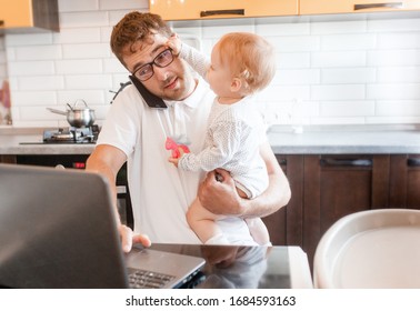 Handsome young man working at home with a laptop with a baby on his hands. Stay home concept. Home office with kids.  - Shutterstock ID 1684593163