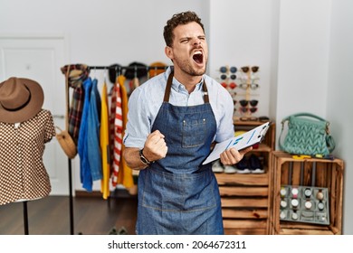Handsome young man working as manager at retail boutique angry and mad screaming frustrated and furious, shouting with anger. rage and aggressive concept. 