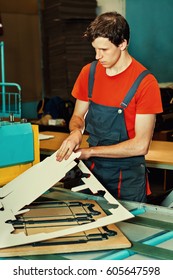 Handsome Young Man Working In Manufacture With Boxes At Factory For The Production Of Cardboard Packaging