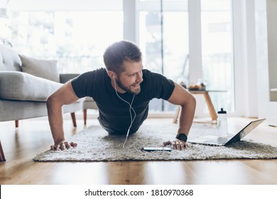 Handsome young man working out at home in the living room 