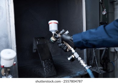 Handsome young mechanic focuses on painting a car part in a professional workshop setting. - Powered by Shutterstock